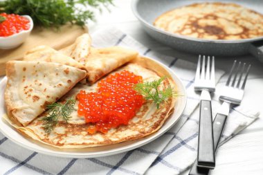 Beyaz ahşap masada servis edilen kırmızı havyarlı leziz krepler.