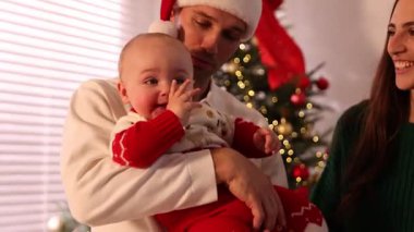 Mutlu ebeveynler, Noel için dekore edilmiş şirin bebekleriyle. Kamera ileri ve geri hareket ediyor