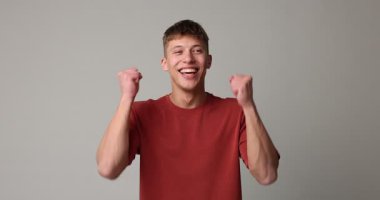 Gri arka planda poz veren mutlu genç adam