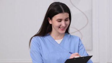 Tıp üniformalı doktor içeride notlar alıyor.