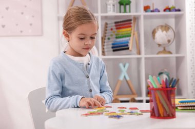 Beyaz masada harflerle alfabe öğrenen küçük bir kız.