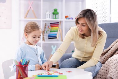 Anne, kızına beyaz masada alfabe öğretiyor.