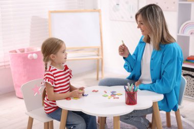 Anne, kızına beyaz masada alfabe öğretiyor.