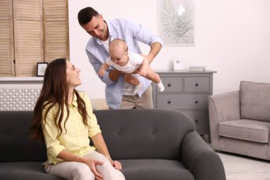 Mutlu ebeveynler evdeki kanepede sevimli bebekleriyle. Metin için boşluk