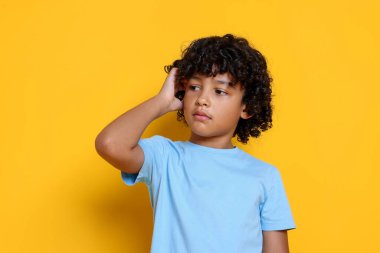 Sarı arka planda düşünceli küçük bir çocuğun portresi.