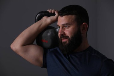 Gri arka planda kettlebell ile egzersiz yapan adam.