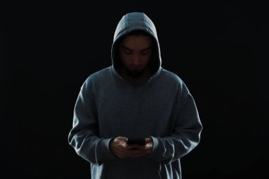 Siyah arka planda akıllı telefonu olan bir suçlu.