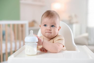 Evinde şezlongda yemek şişesi olan sevimli bir bebek.