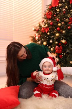 Mutlu anne ve tatlı bebeği Noel için dekore edilmiş odada.