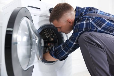 Tamirci evde bozuk çamaşır makinesini tamir ediyor.