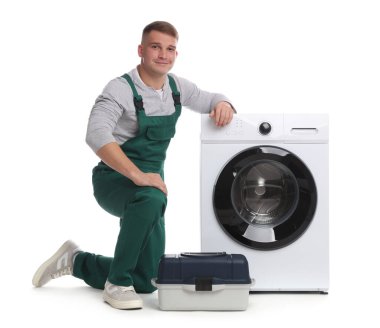 Beyaz arka planda çamaşır makinesi ve alet çantası olan üniformalı bir tamirci.