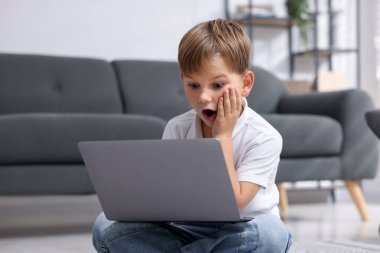 Siber tehlike. Evde dizüstü bilgisayar kullanan korkmuş küçük bir çocuk.