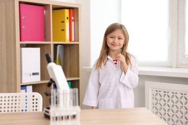 İçinde mikroskop ve test tüpleri olan sevimli küçük bir kız. Çocuk ve bilim