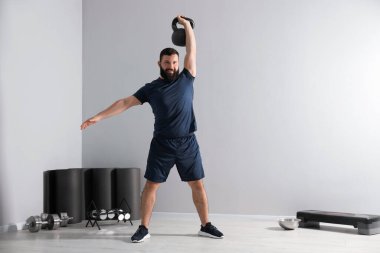 Güçlü adam spor salonunda kettlebell ile egzersiz yapıyor, mesaj için yer var.