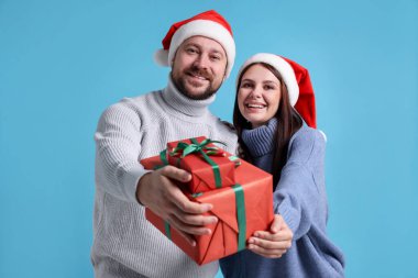 Açık mavi arka planda Noel hediyeli mutlu çift