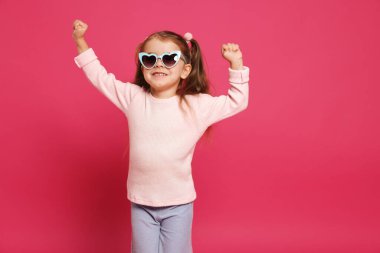 Pembe arka planda güneş gözlüklü gülümseyen küçük kız. Metin için boşluk
