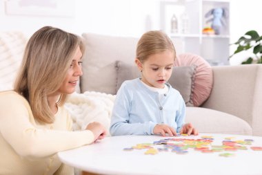 Anne, kızına beyaz masada alfabe öğretiyor.