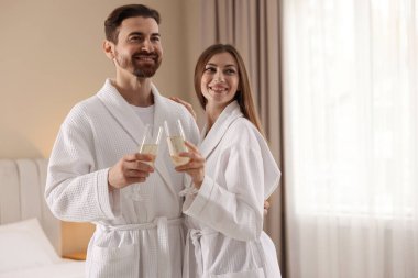 İçeride köpüklü şarap bardakları olan bornozlu mutlu bir çift. Metin için boşluk