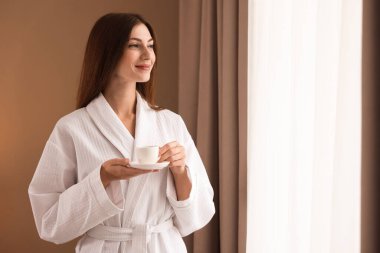 Bornozlu güzel bir kadın, pencerenin yanında sabah kahvesi var. Metin için boşluk