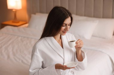 Bornozlu güzel bir kadın, sabah kahvesi evde, yatakta.