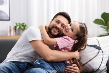 Mutlu bir babanın evdeki kanepede kızını kucaklaması. Aile bağı