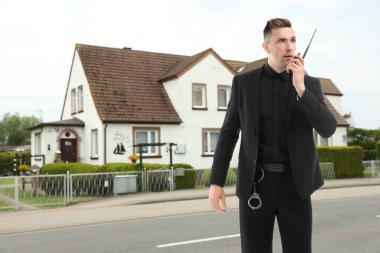 Üniformalı güvenlik görevlisi evin yakınında telsiz kullanıyor. Özel mülk koruması