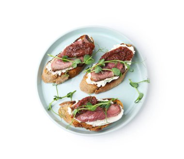 Biftek, krem peynir, güneşte kurutulmuş domatesler ve beyaz üzerine izole edilmiş mikro yeşillikler.