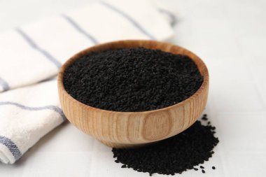 Kasedeki siyah kimyon tohumları beyaz karolar üzerinde, yakın plan.