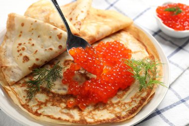 Masadaki ince kreplere kırmızı havyar ekliyorum, yakın plan.