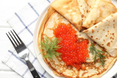 Beyaz ahşap masada servis edilen kırmızı havyarlı leziz krepler.