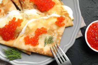 Lezzetli krepler kırmızı havyarlı ve ekşi kremalı siyah desenli masa, düz.