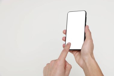 Man holding smartphone with blank screen on white background, closeup. Mockup for design