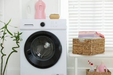 Çamaşır sepetinin yanında çamaşır makinesinin yanında temiz kıyafetler var.