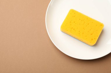 Kahverengi arka planda mutfak süngeri ve plaka, üst manzara. Metin için boşluk