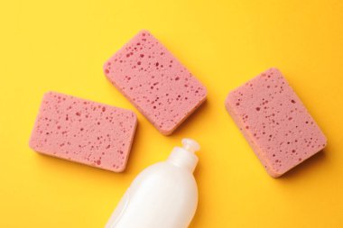 Sarı arka planda mutfak süngerleri ve bulaşık deterjanı.