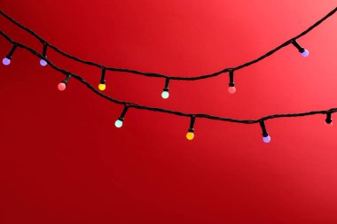 Kırmızı arka planda parlak Noel ışıkları, yakın plan. Metin için boşluk