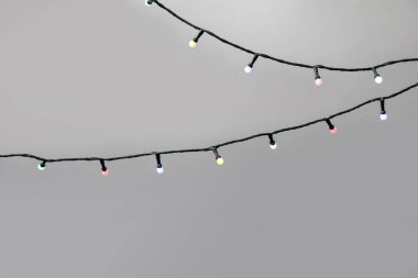 Gri arka planda parlak Noel ışıkları, yakın plan