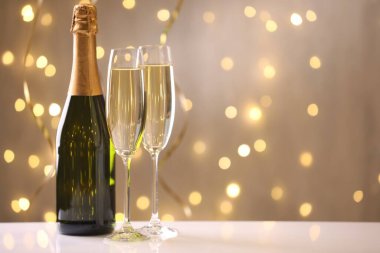 Mutlu Noeller ve mutlu yıllar. Beyaz masada bulanık ışıklara karşı köpüklü şarap ve şişe ile flüt bardakları. Metin için boşluk