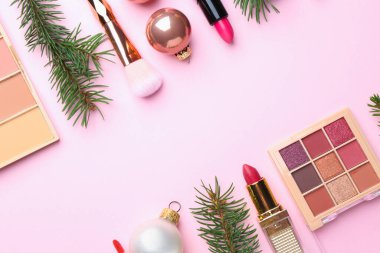 Kozmetik ürünleri ve pembe arka planda köknar dallarıyla Noel kompozisyonu. Metin için boşluk