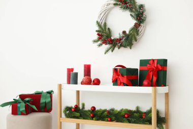 Noel süsü ve yanan mumlar beyaz duvarın yanındaki konsol masasında. İç tasarım