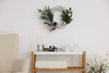 Noel süsü ve yanan mumlar beyaz duvarın yanındaki konsol masasında. İç tasarım