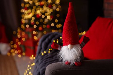 Süslü odada koltukta komik bir noel cücesi, yakın plan. Metin için boşluk