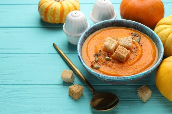 Tohumlu ve kızarmış ekmekli lezzetli balkabağı kremalı çorba açık mavi ahşap masada servis edilir, yakın plan. Metin için boşluk