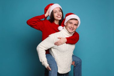 Noel Baba şapkalı gülümseyen çift açık mavi arka planda eğleniyor. Mutlu Noeller ve mutlu yıllar.