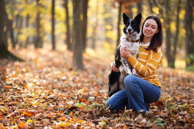 Sonbahar parkında sevimli köpeğini gezdiren bir kadın.
