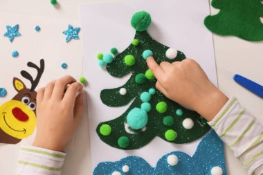 Küçük çocuk Noel kartpostalı hazırlıyor. Çocuk el yapımı.