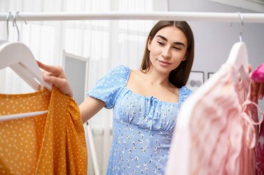 Çekici kadın iç mekânda elbise seçiyor.