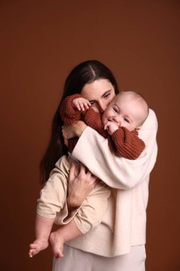 Kahverengi arka planda sevimli bebeği olan anne.