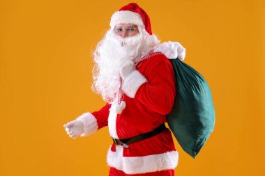 Sarı arka planda çantası olan Noel Baba. Mutlu Noeller ve mutlu yıllar.