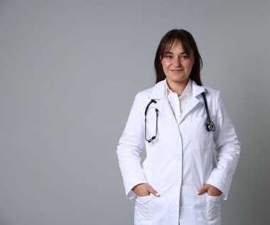 Gri arka planda steteskobu olan tıp üniformalı bir doktor. Metin için yer var.